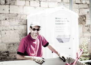 Mitarbeiter vor einer transportierbaren Toilette