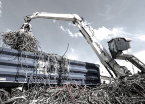 Weißer Bagger mit Aufschrift Aulfinger verlädt Kabel in einen blauen LKW