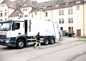 Weißes Umleererfahrzeug hält auf Straße um Mülleimer zu leeren