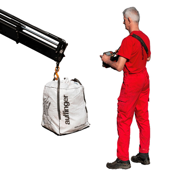 Ein Big Bag an einem Haken mit einem Mitarbeiter rechts im Bild